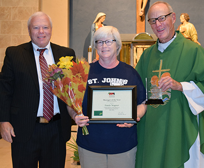 MANAGER OF THE YEAR - Paula Wagner was recently honored by principal Dennis Martin (left) and chief administrative officer Father Lyle Johnson.